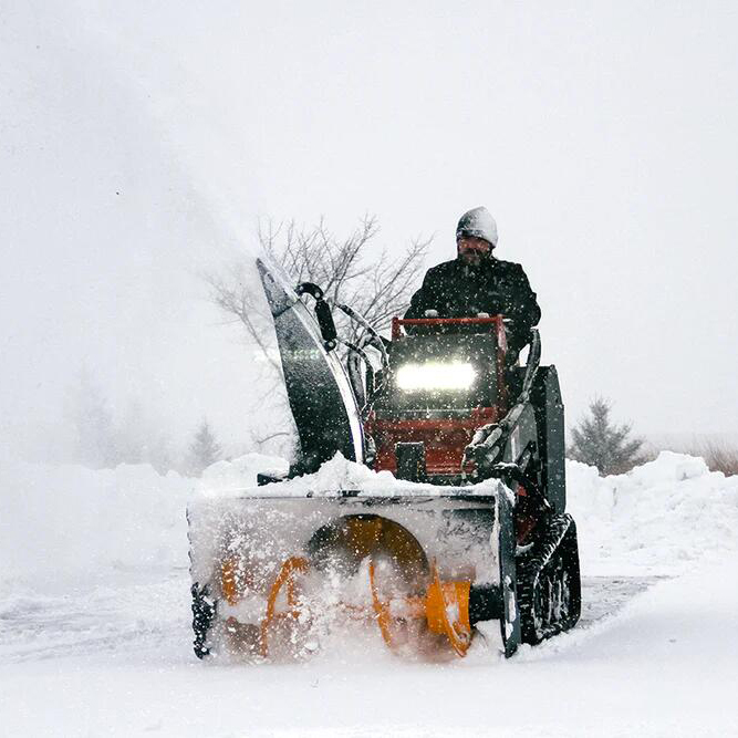front mount snow blower removing heavy snow from a roadway