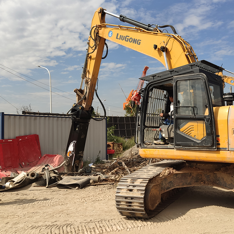 excavator scrap shear operating beside mixed metal waste in yard