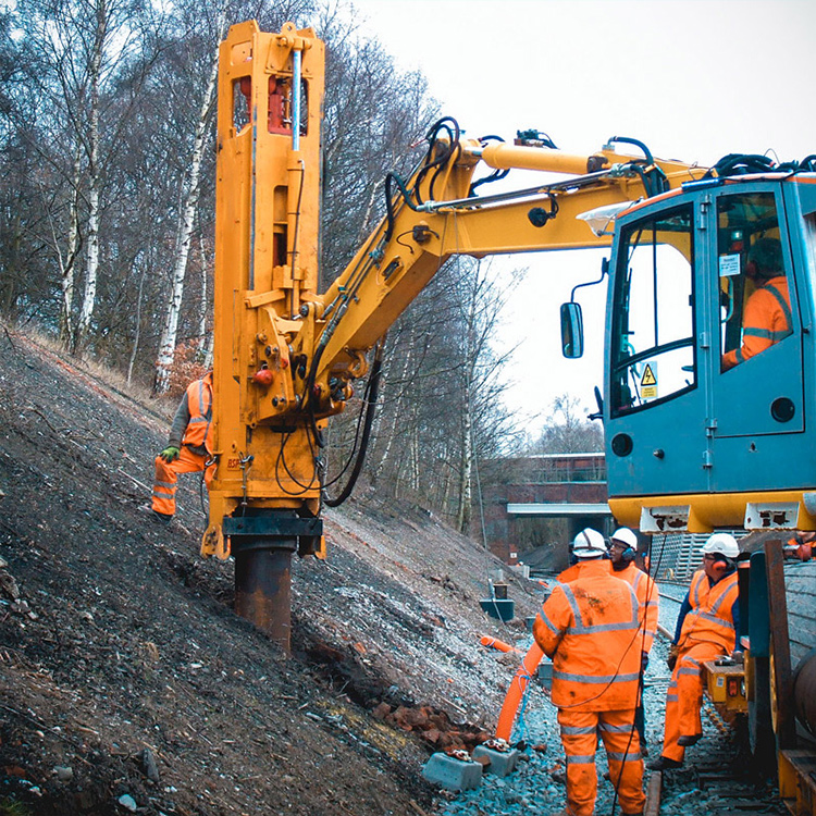 Excavator piling hammer working on embankment construction site