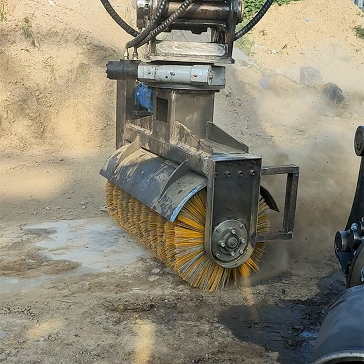 Excavator rotating brush sweeping sand and dirt on rough ground