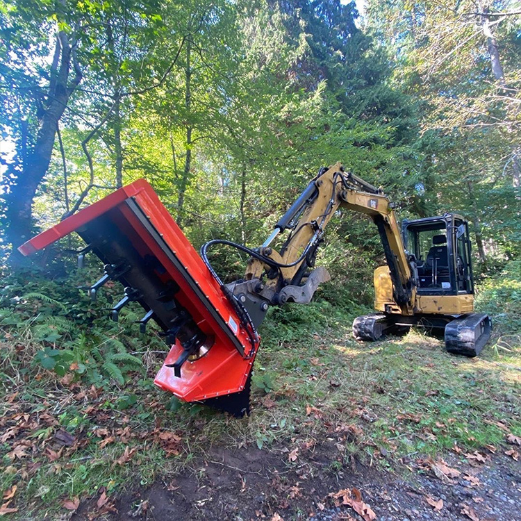 Excavator flail shredder clearing dense brush with a mini excavator in forest