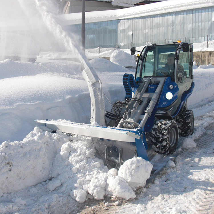 wheel loader snow blower clearing deep snow near a facility